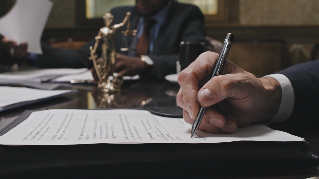 Close-up of a hand signing legal documents at a lawyer's office