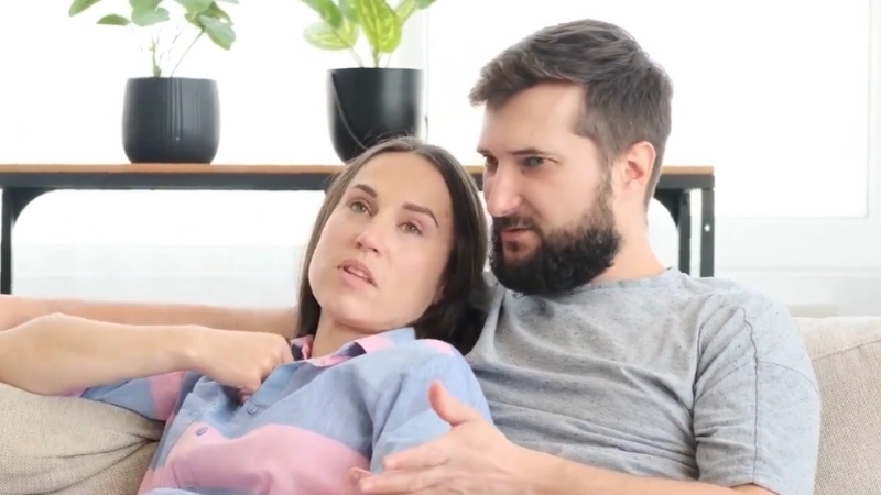 A Couple Sits Together on A Couch, Engaged in A Conversation, with One Person Expressing Their Thoughts