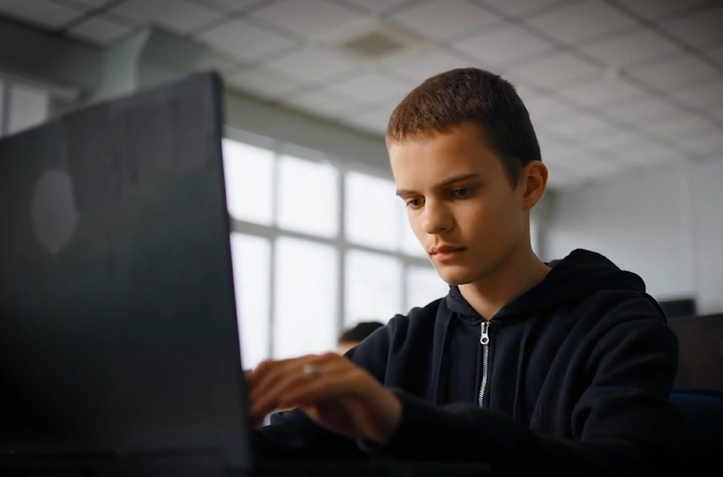 Boy using a computer in a school classroom, focused and engaged