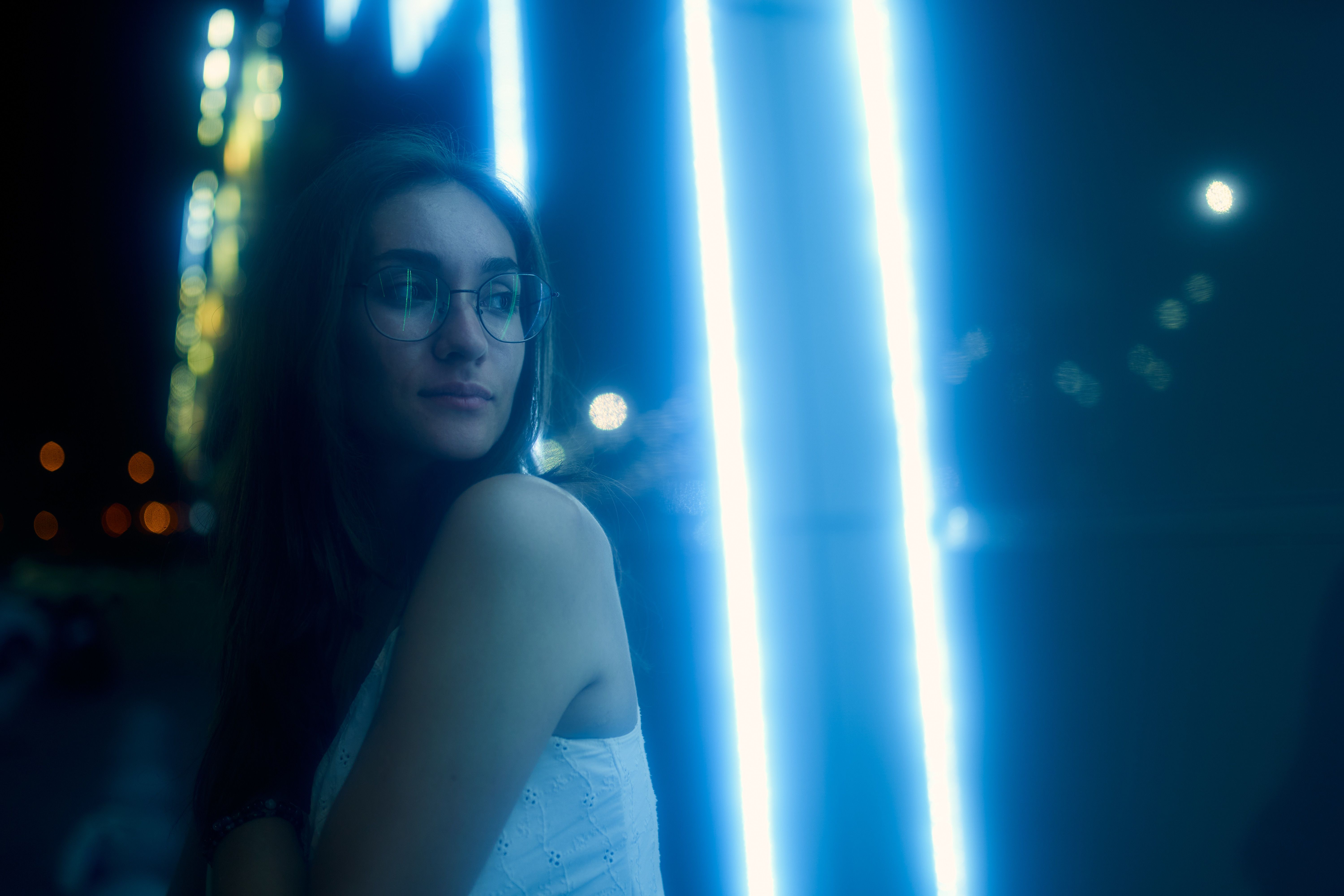 A thoughtful woman near city lights at night, suggesting identity, emotional labor, and the boundaries of companionship work.