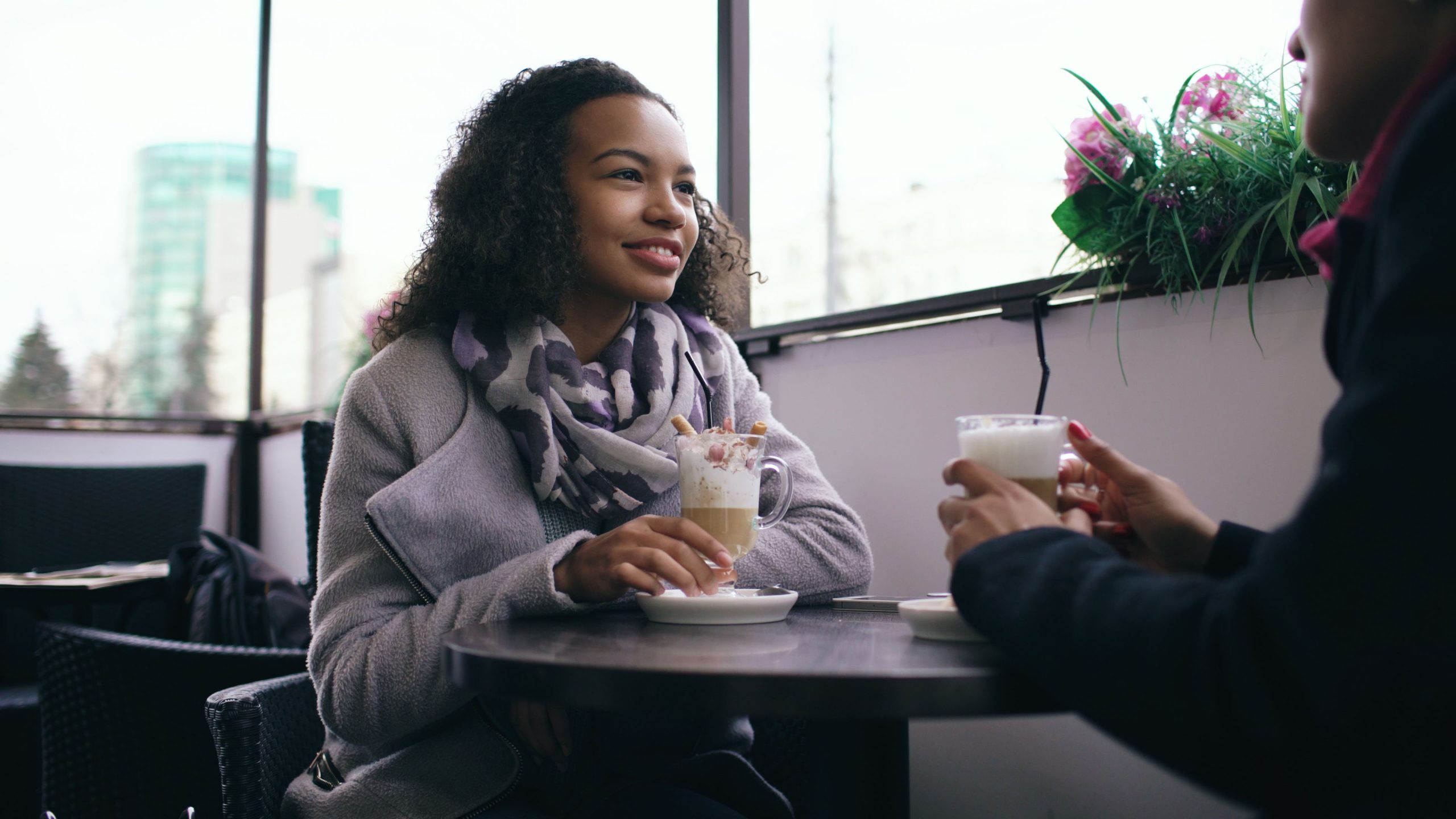 Two adults sharing coffee and conversation in a relaxed cafe, illustrating the appeal of attentive companionship.