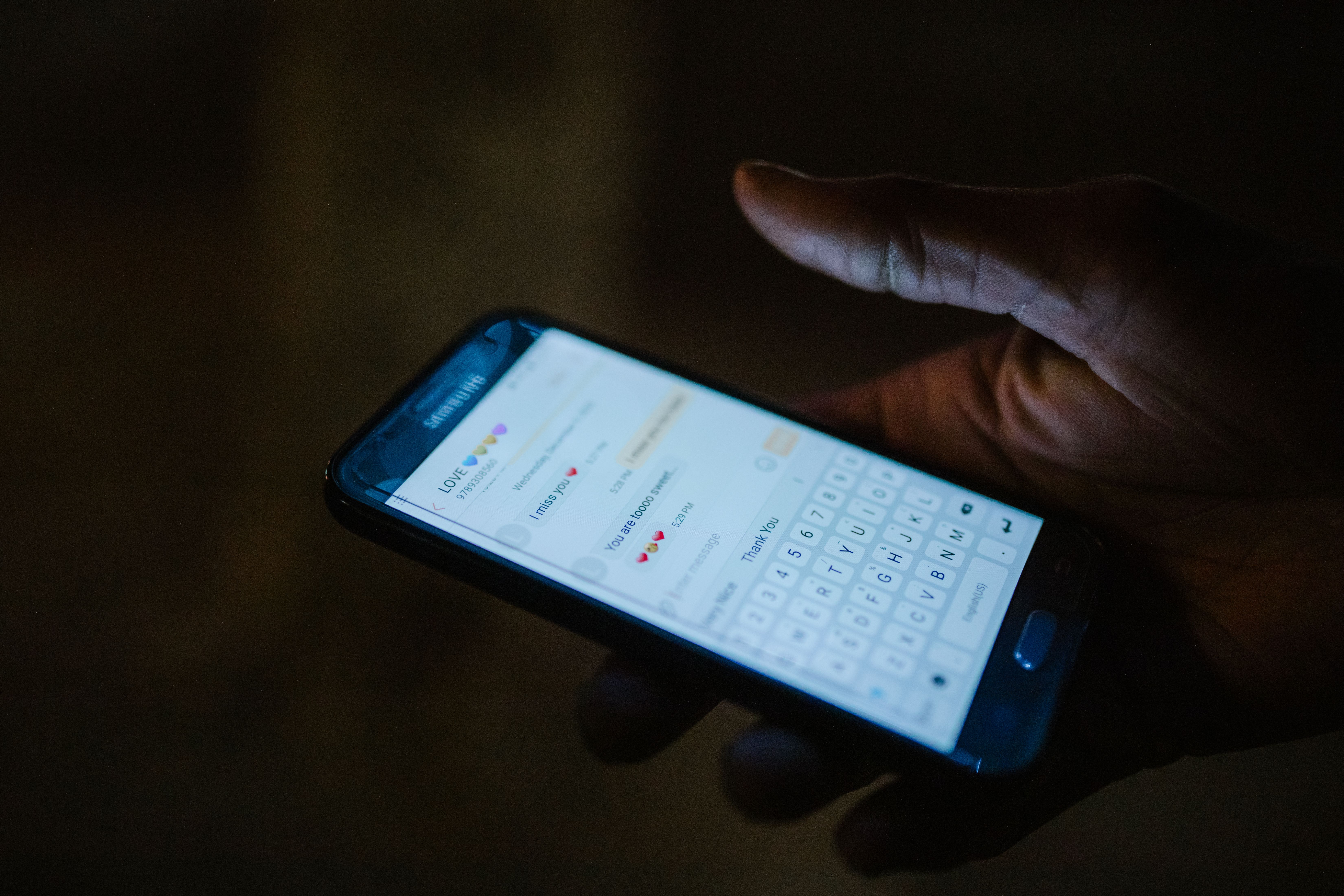 A hand holding a smartphone with a messaging app open, representing digital matchmaking and client communication.