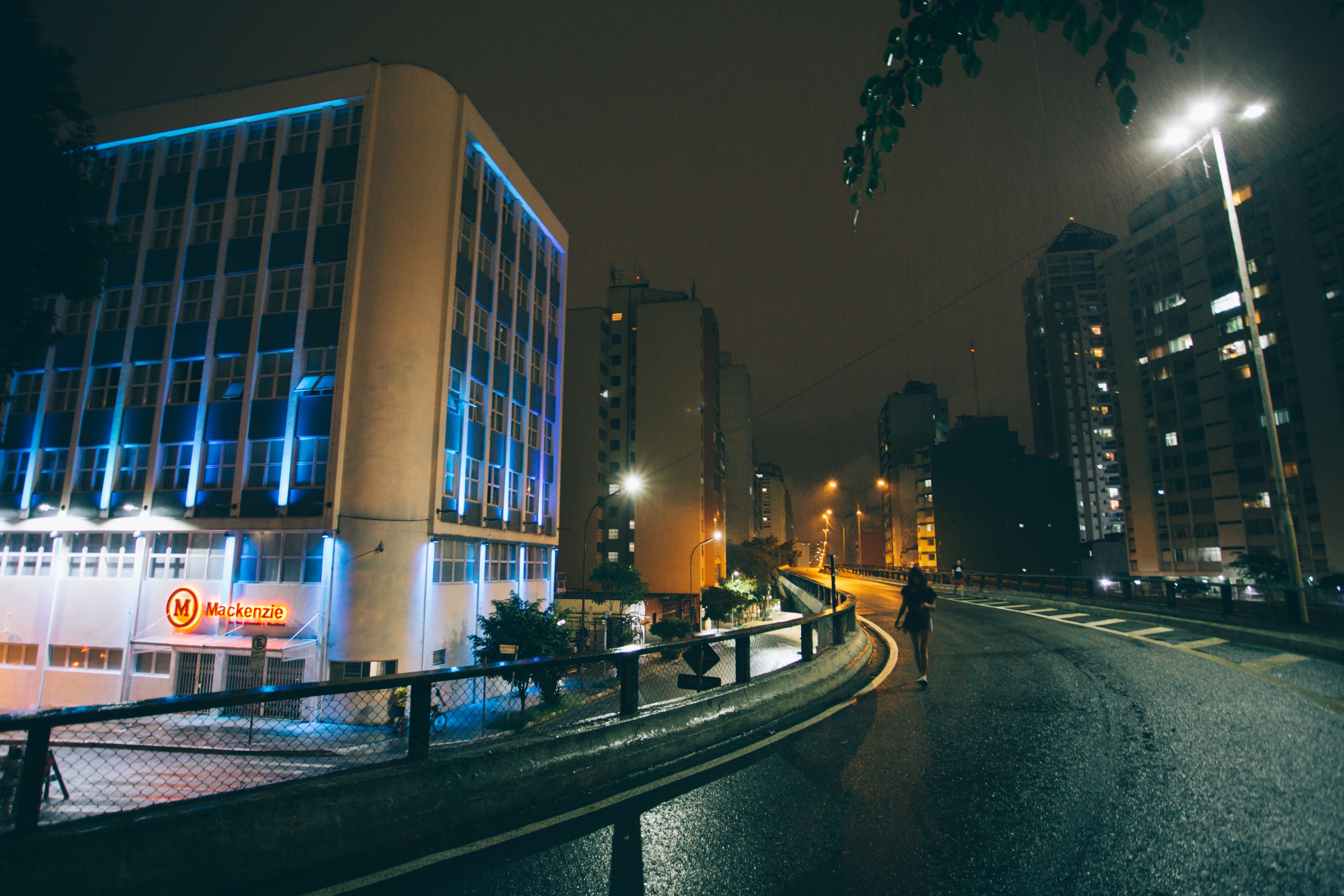 A solitary person walking through an illuminated city at night, representing urban loneliness and the demand for connection.